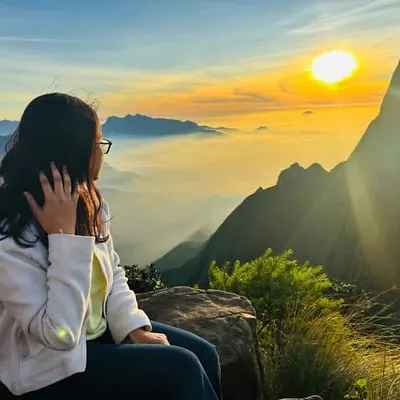 A traveler watching the sun rise over a sea of clouds at Kolukkumalai. This is a core memory from our Munnar trip.
