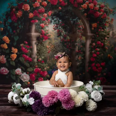 A huge, happy grin from this baby during her floral milk bath session. The tub is surrounded by beautiful flowers, creating a whimsical garden feel.