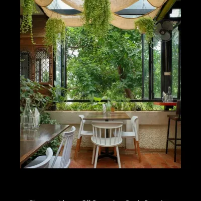 The seating area at Champaca is designed to feel like a veranda, blurring the line between indoors and outdoors. Hanging plants and large, openable windows make the surrounding nature a key element of the decor.