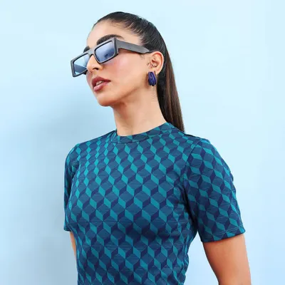 Capturing the energy on set. This look features a geometric print top and bold, modern sunglasses, showcasing a minimal yet impactful street style aesthetic.