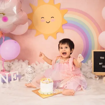 A first birthday cake smash full of sunshine and rainbows. This little one is having the best time with her personal cake in our custom "You Are My Sunshine" themed setup.