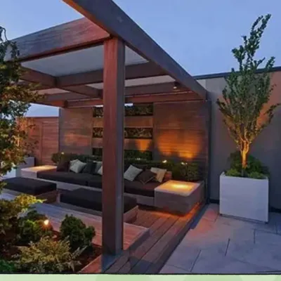 This modern pergola demonstrates how to create a cozy and stylish outdoor living room. The structure provides partial shade and a frame for lighting, while the integrated seating and planters make the space both comfortable and green.