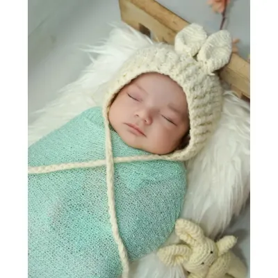 A peaceful close up of a sleeping newborn. I use soft wraps and adorable props like this knit bunny hat to create sweet, serene images of your baby.