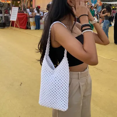 This is our classic white macrame shoulder bag, pictured at a local flea market. Its simple, open-knot design is lightweight and perfect for a sunny day out.