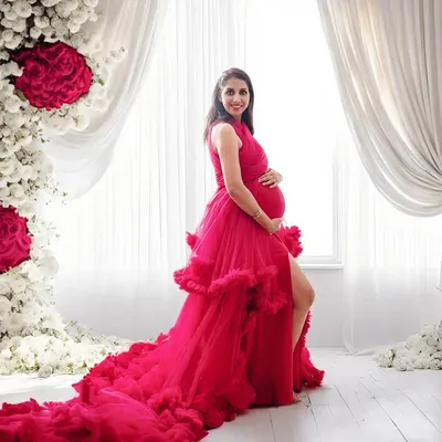 A truly showstopping look. This vibrant ruffled gown paired with a floor-to-ceiling floral arch creates a glamorous and unforgettable maternity portrait.