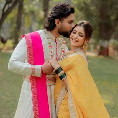 A gentle kiss on the forehead captures the tenderness of this couple's bond. This close-up highlights the groom's traditional attire and the bride's joyful expression during their outdoor Marathi-themed pre-wedding shoot.