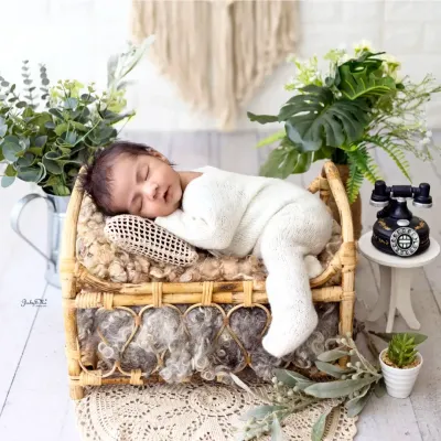 This little one looks so peaceful sleeping on a miniature cane bed. I use natural textures and a soft, neutral color palette to create a calm and timeless newborn portrait.