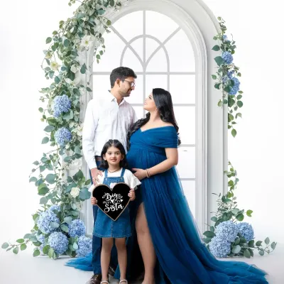 The whole family is excited to meet their new "Brother & Bestie." This beautiful portrait is framed by a stunning floral arch, with the older sister proudly holding a sign to celebrate her new role.