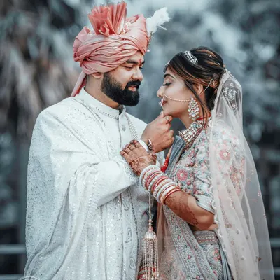 A tender moment between the bride and groom on their wedding day. The groom gently holds his bride's chin, their gazes locked in a portrait that is both intimate and beautifully composed.