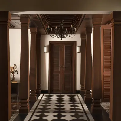 The main corridor, a grand promenade flanked by traditional Chettinad pillars. The classic checkerboard floor and coffered wooden ceiling establish a narrative of timeless Indian elegance.