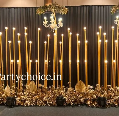 This is a full view of our popular gold and black sangeet stage. The design uses tall, illuminated pillars and elegant chandeliers against a dark backdrop to create a look of pure glamour and sophistication.