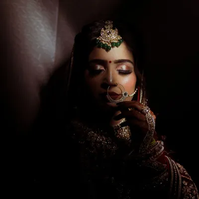 Using shadow and light to create a dramatic and soulful bridal portrait. This shot focuses on the bride's serene expression and the intricate details of her maang tikka and nath, creating a timeless, artistic image.