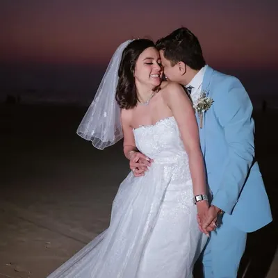 A beautiful moment from a Catholic wedding on a Goa beach. The groom's gentle kiss and the bride's happy smile capture the joy of the day.