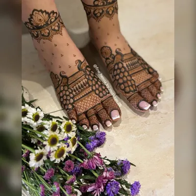 An elegant foot mehndi design with peacock motifs and a delicate dotted pattern.