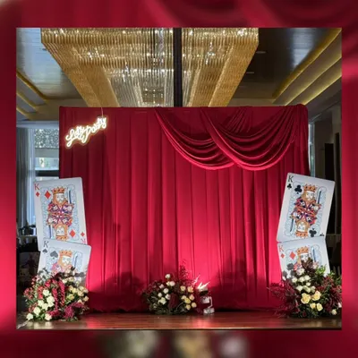 A grand reveal for a 75th birthday bash. The stage is set with dramatic red velvet curtains and oversized "King" playing cards, promising a night of royal casino fun.