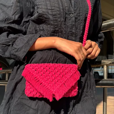 This bright pink macrame sling bag is all about the details. The intricate knotting and fringed envelope flap give it a boho-chic feel, making it a standout accessory.