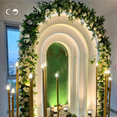 For an intimate home ceremony, we designed this modern and romantic backdrop. The layered arches, soft backlighting, and a lush floral garland of white roses created a dreamy focal point for the couple to exchange their promises.