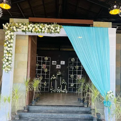 A simple and elegant entrance decor we did for a home event. The combination of white and light blue drapes with a classic white floral arch creates a fresh and welcoming look for your guests.