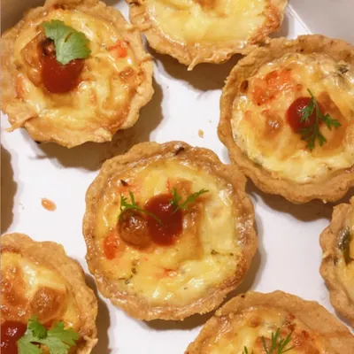 A box of my yummylicious chicken tarts, baked to perfection. The flaky pastry shells are filled with a creamy chicken and vegetable filling and topped with melted cheese.