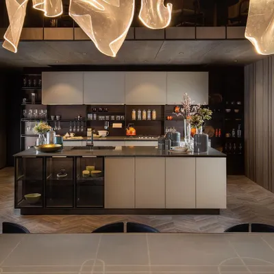 This open-plan modular kitchen features a central island that serves as both a preparation area and a concealed crockery unit. Integrated backsplash storage keeps countertops uncluttered, maintaining a seamless look that flows into the living room.