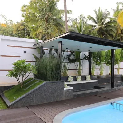 A modern poolside gazebo I designed and built, featuring a sunken seating area. The structure is integrated with planters containing tall grasses and a small tree on a berm, blending architecture with the landscape.