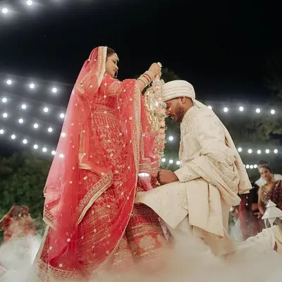 A magical Varmala moment, as the bride places the garland on the groom under a sky of string lights and surrounded by ethereal smoke.