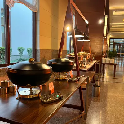 A sleek and modern buffet setup for an indoor event. This arrangement features contemporary black and brass serving dishes on rustic wooden tables, perfectly matching the sophisticated ambience of the venue.