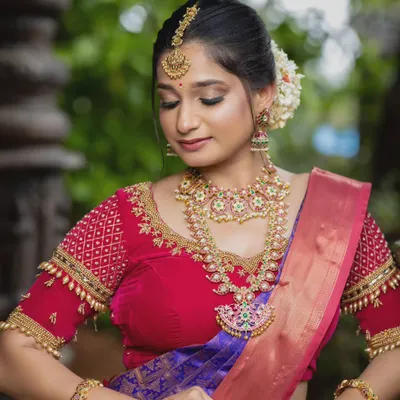 A stunning South Indian bridal look featuring a vibrant Kempu jewellery set. The rich red and green stones in the necklace and haram add a beautiful pop of color against the silk saree.