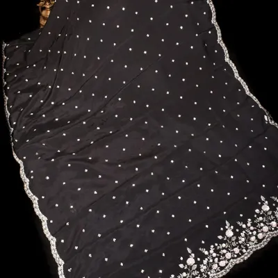 A stunning black georgette saree with delicate white polka dots and an exquisitely embroidered floral border in silver. This is a timeless piece for any elegant evening affair.