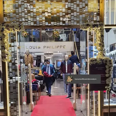 For the anniversary of this Louis Philippe showroom, we set up a classic red carpet entrance framed with a delicate floral arch. This kind of retail decoration helps create an exclusive experience for shoppers during a special event.