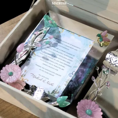 A close-up of the Daisy Collection wedding invite, nestled in a silver-plated frame adorned with delicate enamel flowers and butterflies. It’s a beautiful keepsake that captures the romance of your story.