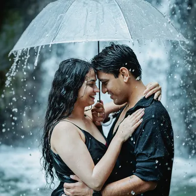 A couple shares an intimate moment under an umbrella during a rain shoot by a waterfall. This is a perfect example of how I create highly romantic and cinematic scenes, no matter the weather.