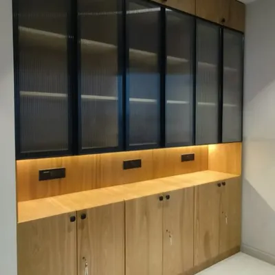 This custom storage unit was designed for a modern office, blending natural wood tones with fluted glass doors. The integrated backlighting provides a warm ambiance while showcasing the items on display.