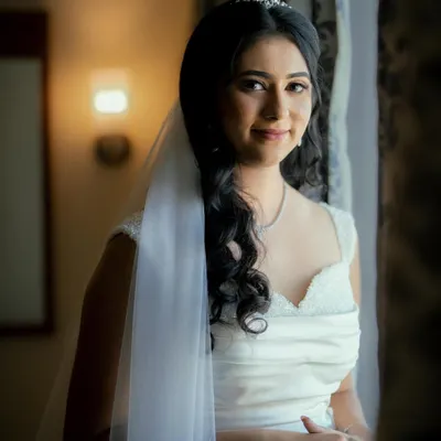 A beautiful portrait of my Christian bride by the window. Her soft glam makeup and simple white gown create a look of pure, understated elegance.