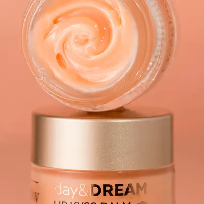 A close-up macro shot of a lip balm, revealing its whipped, creamy texture. The image is clean and focused, designed to make the product look appealing and luxurious. The lighting highlights the swirl in the balm, adding a sense of craftsmanship.
