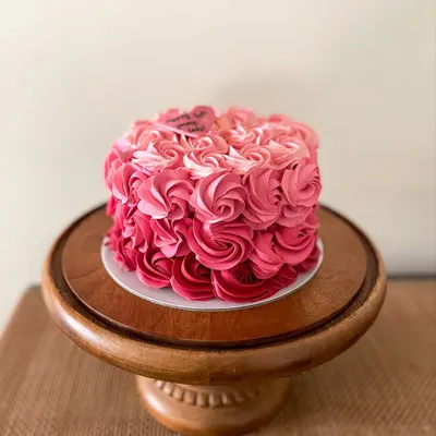 A beautiful cake featuring pink ombre buttercream rosettes. This design is perfect for birthdays and anniversaries, with a little heart plaque that reads "Happy 50th young lady!"