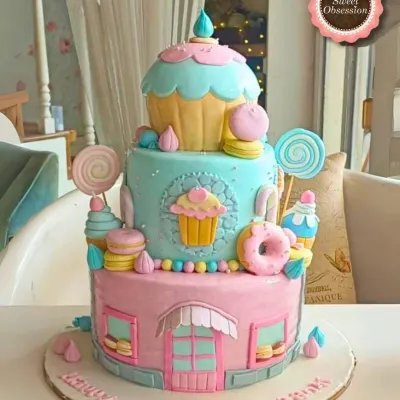 A whimsical three-tier candy shop cake in pastel colors, adorned with fondant cupcakes, donuts, and lollipops.