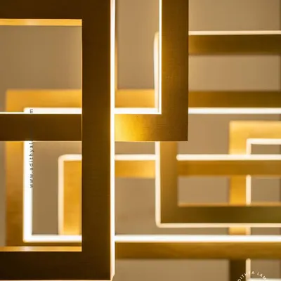 A multi-layered chandelier composed of intersecting rectangular frames with a brushed gold finish. The integrated LEDs cast a warm, ambient light, creating a dynamic and architectural statement piece for modern interiors.