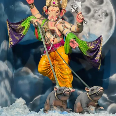 The final look of this celestial-themed Ganpati pandal. The murti appears to be floating through the clouds, an effect created by the hand-painted backdrop of the moon and a floor covered in cotton to look like clouds.