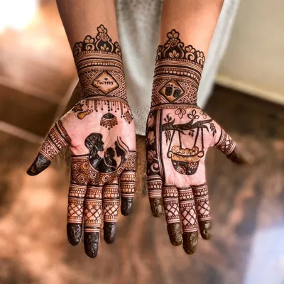 A very special baby shower mehendi for a mother expecting twins. One hand features a silhouette of parents with a baby, and the word 'Twins' is written on the wrist. The other hand has a drawing of a baby in a traditional cradle.