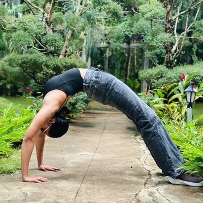 A deep Urdhva Dhanurasana (Wheel Pose) in a garden. This powerful backbend opens the entire front of the body and builds strength in the arms, legs, and spine.