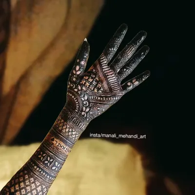 A beautiful example of a full-hand traditional mehandi design. The pattern uses fine lines, dots, and geometric shapes to create a dense and intricate look, with the name 'Nikhil' subtly included.