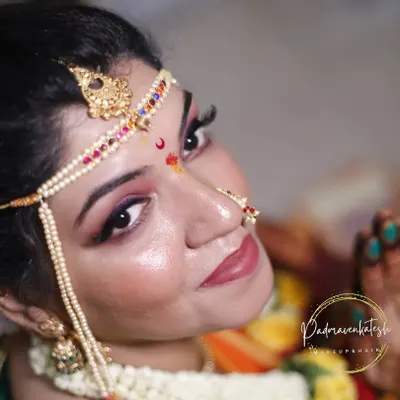 A close-up of a Maharashtrian bride. This shot beautifully captures the traditional 'mundavalya' (forehead ornament) and the distinct crescent bindi, which are key elements of this look.