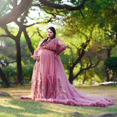 A princess moment in the park. This beautiful pink tulle gown looks absolutely dreamy against the soft green backdrop, creating a fairytale maternity portrait.