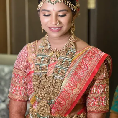 Glowing in her wedding beauty, this enchanting bride radiates sophistication and bliss. Her look features a red and gold saree with heavy temple jewellery, and a soft, radiant makeup finish.
