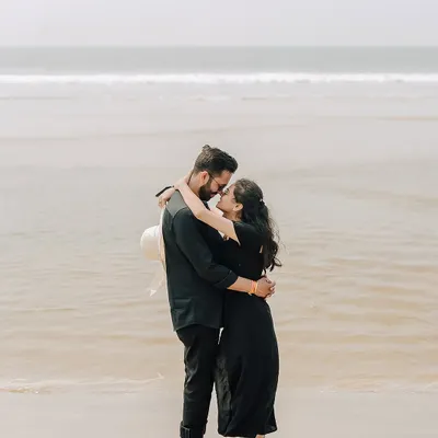 An intimate moment in the gentle waves of a Goan beach. This silhouette against the bright sea creates a timeless and romantic image of the couple's connection.
