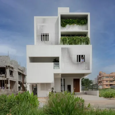 The LUCID House, a contemporary residential building designed for an urban setting. The facade features stacked, box-like volumes with integrated planters and a distinctive perforated screen, showcasing a modern architectural language.