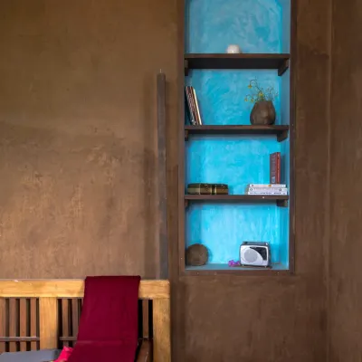 The simplicity of a plain mud wall is its greatest strength. In this Doddaballapura mud house, an arched niche plastered in a vibrant blue oxide provides a striking contrast to the earthy brown, showcasing a simple yet powerful design choice.