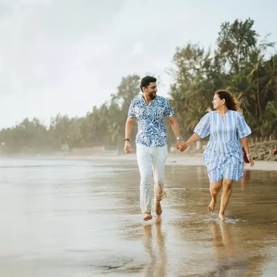 A happy, candid shot of a couple running along the shoreline. This image is full of energy and joy, capturing a perfect moment of fun during their beach pre-wedding shoot.