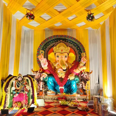 An outdoor pandal decoration for Ganesh Chaturthi. This setup features a yellow and white draped structure to house the large Ganesha idol, creating a grand space for the festival.